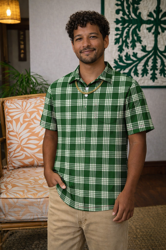 Man wearing a green plaid shirt standing in a room with a couch and decorative wall art.